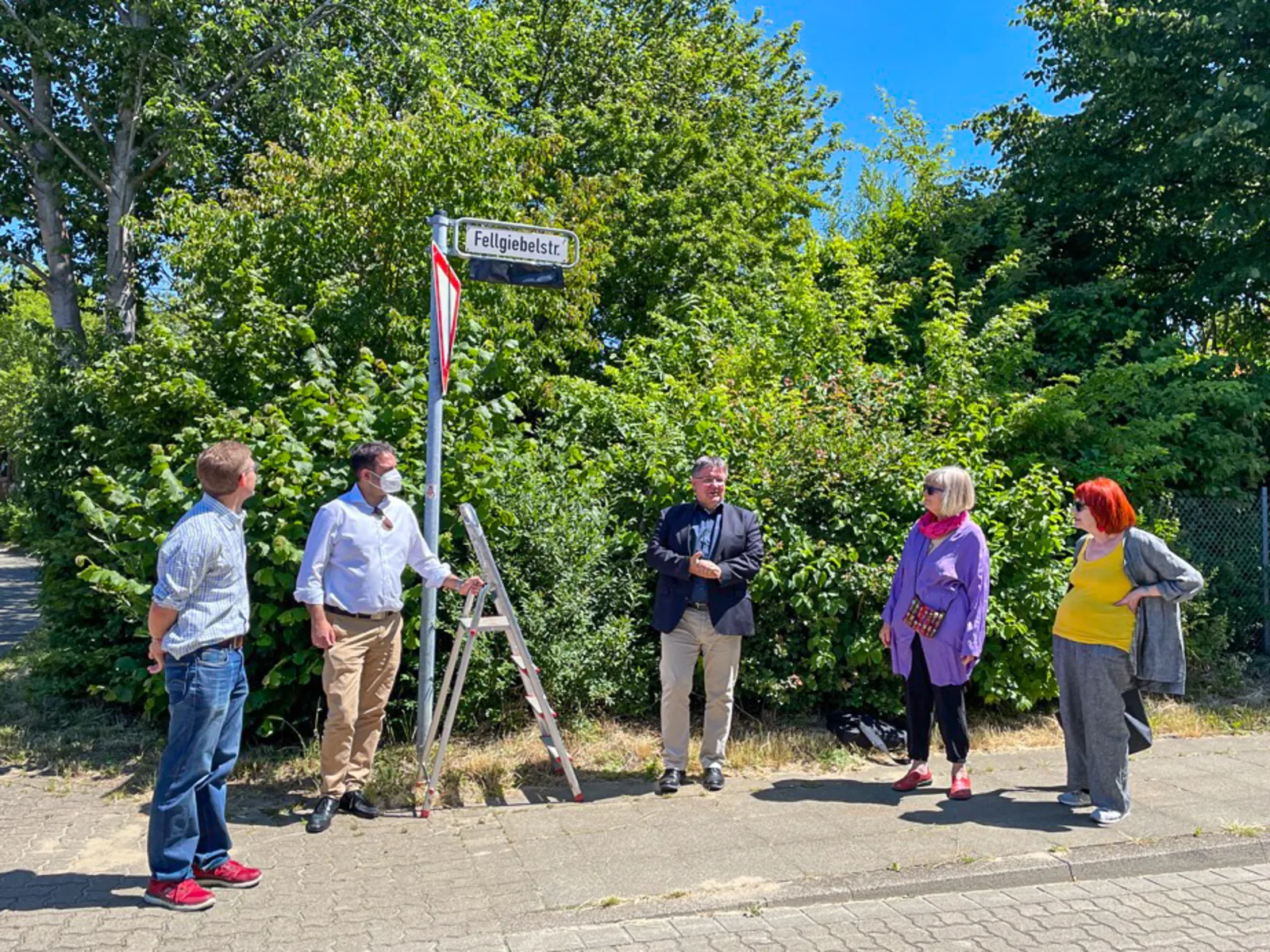 Fünf Personen vor einem Straßenschild.